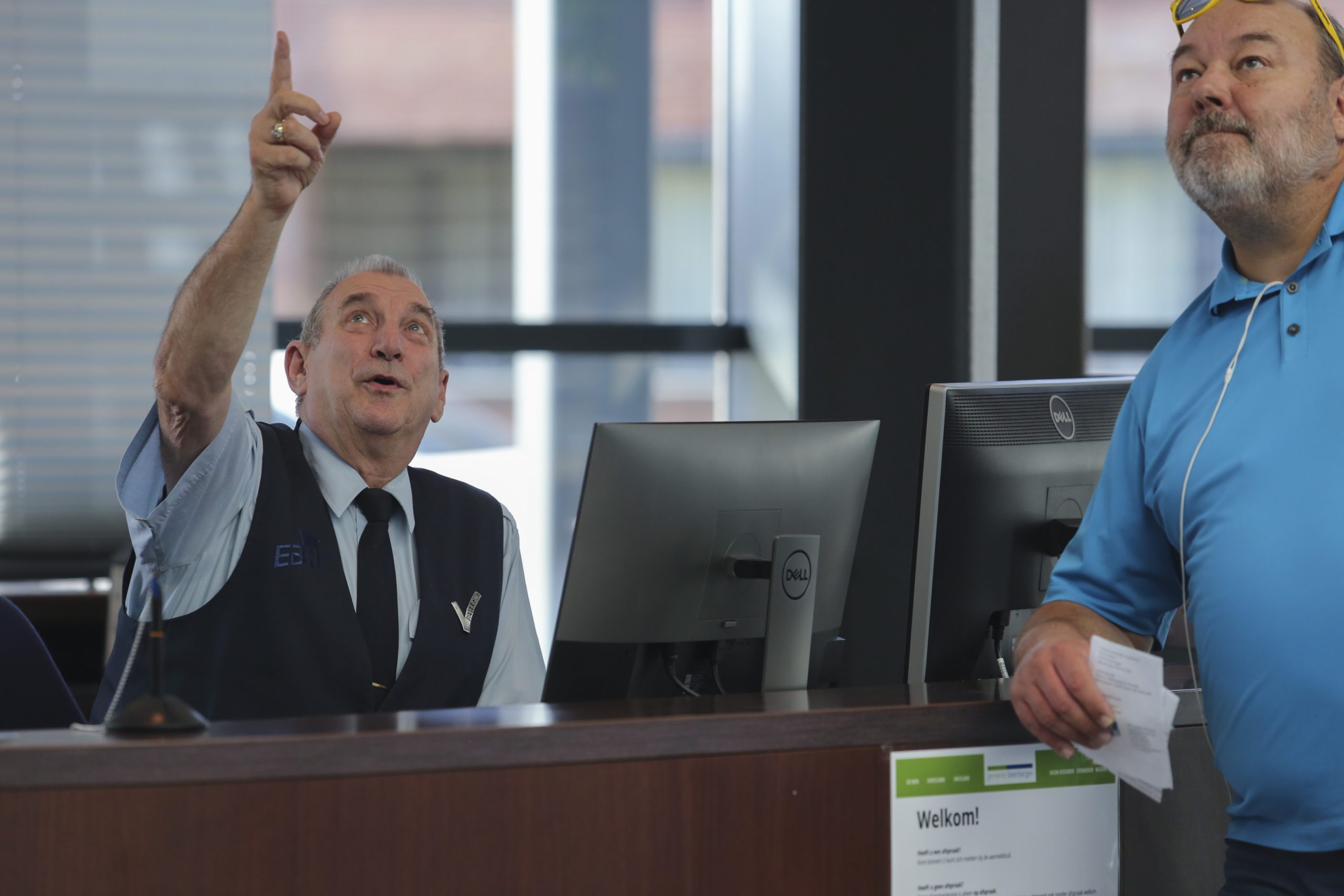 Hospitalitymedewerker wijst een bezoeker de weg bij de balie