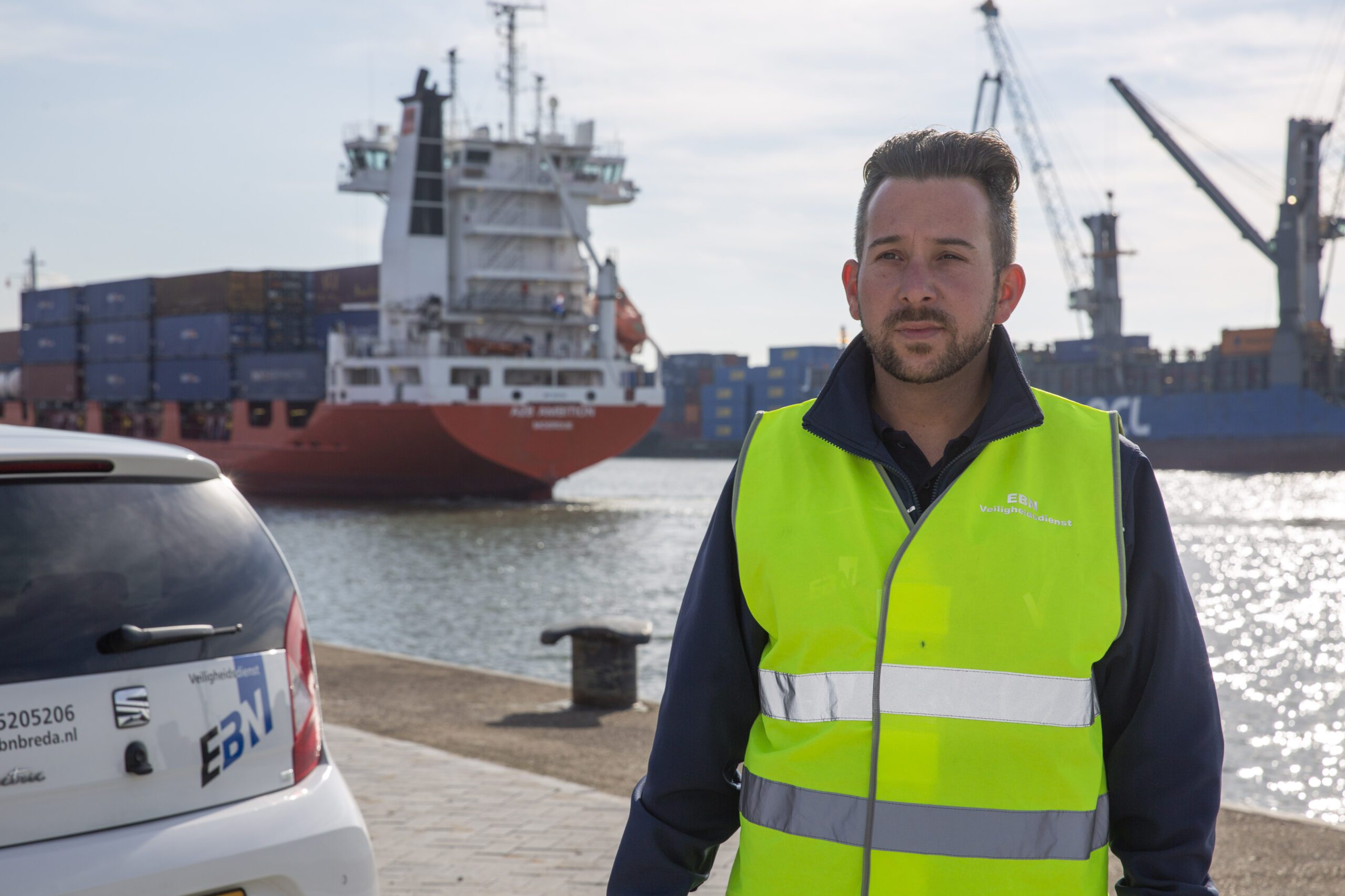 EBN-medewerker in signaalhesje op de kade bij een containerschip