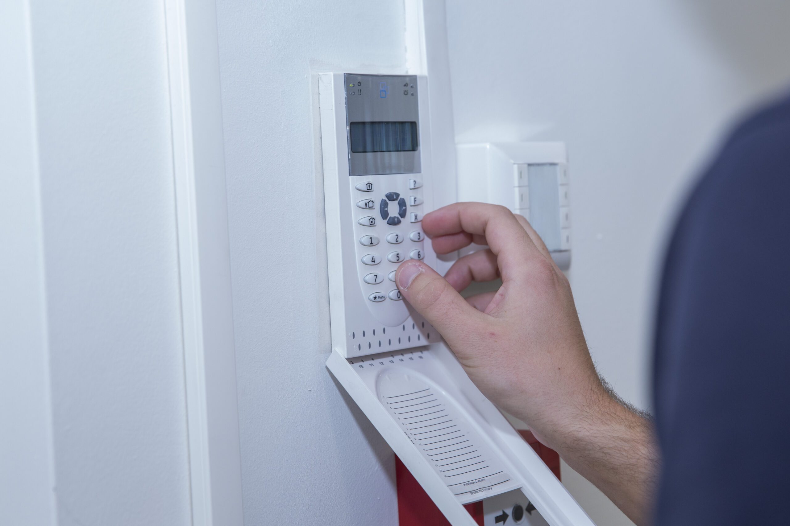 Hand toetst een code in op het bedieningspaneel van een alarmsysteem