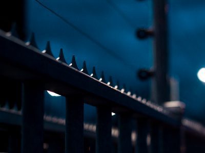 Spijlenhek met punten bij nacht, verlicht door straatlantaarns